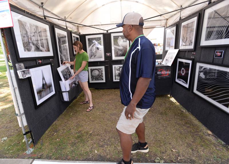 Emily Frederick of Glen Ellyn takes a look at some of the prints made by photographer Mike Baker of Bolingbrook during the Glen Ellyn Art Festival on Sunday, Aug 24, 2024 at Lake Ellyn.