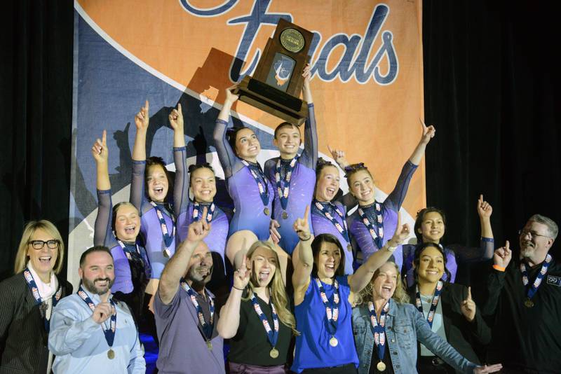 Members of the Downers Grove South gymnastics team celebrate with their first-place trophy during the girls state gymnastics meet at Palatine High School on Saturday, Feb. 22, 2025.
