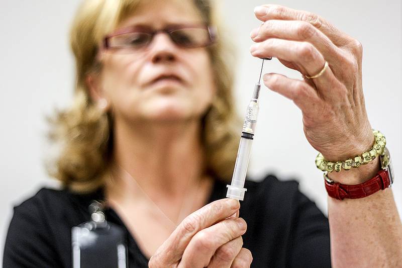 Carol Waggoner, a registered nurse, measures out a vile of the flu vaccine Thursday while giving flu shots at the McHenry County Department of Health in Crystal Lake.