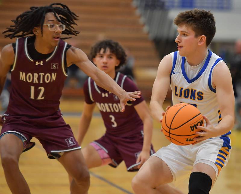 Lyons Township's Danny Janiszewski (right) pauses his drive before laying the ball up as Morton's Chas Ontiveros (12) defends during a Thanksgiving Tournament game on November 25, 2024 at Lyons Township High School in LaGrange.