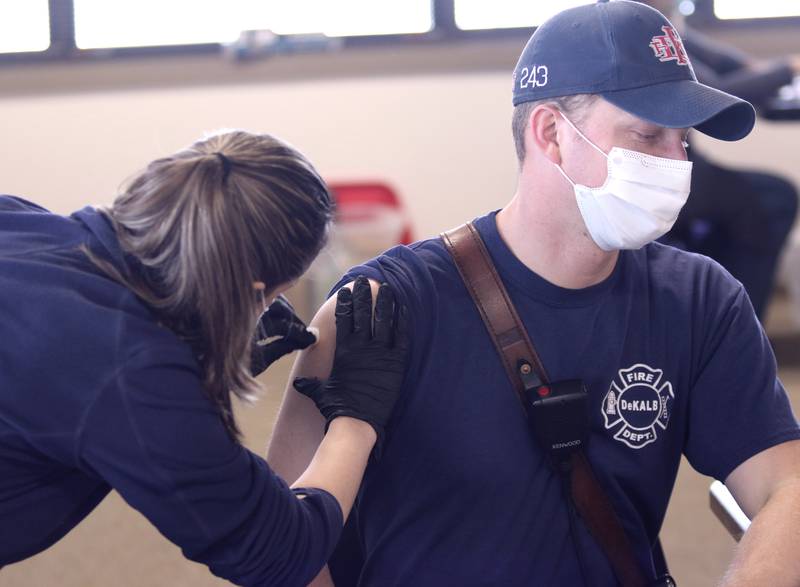 Todd Adamson, a City of DeKalb firefighter/paramedic, has his arm swabbed prior to receiving the Moderna COVID-19 vaccine from DeKalb County Health Department public health nurse Alex Diehl Thursday in DeKalb.