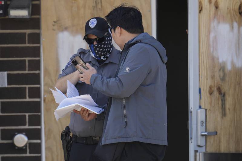 A person talks to a masked guard at the entrance of an immigration processing center Monday, Sept. 8, 2025, in Broadview, Ill., a suburb of Chicago. (AP Photo/Carolyn Kaster)