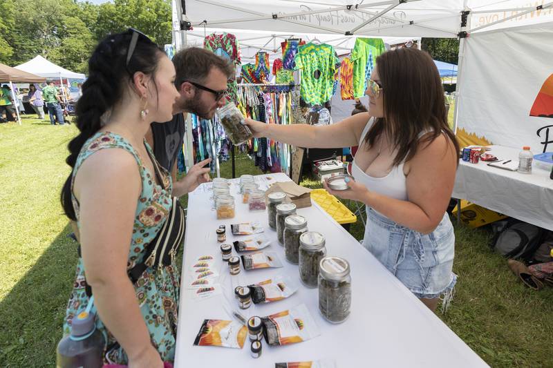 Jon and Tegan Poitras take a whiff of bud supplied by Selina Banker Friday, July 12, 2024 as part of Herbal Roots’ Cannafest at Elks Page Park. Banker is part of Peaceful Pines Hemp Farm.