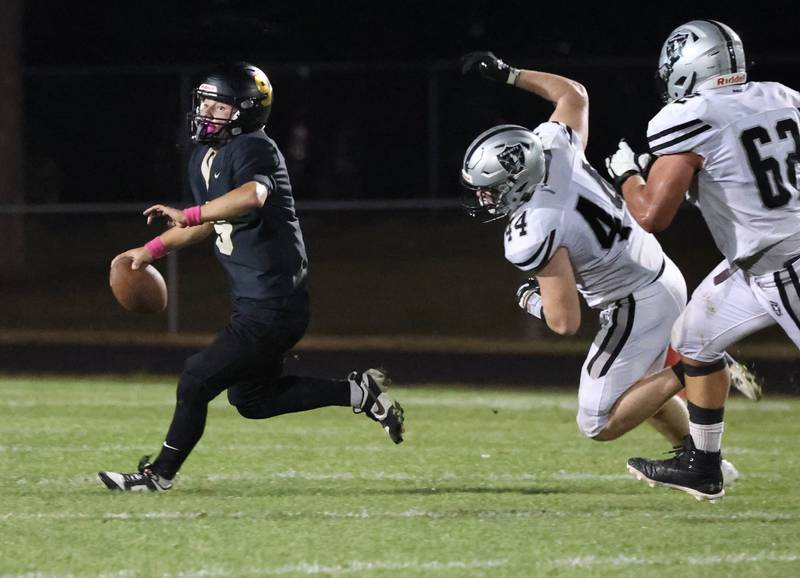 Sycamore's Griffin Larsen tries to avoid the rush of Kaneland's Rogan O’Neil (left) and Jake Buckley during their game Friday, Oct. 3, 2025, at Sycamore High School.