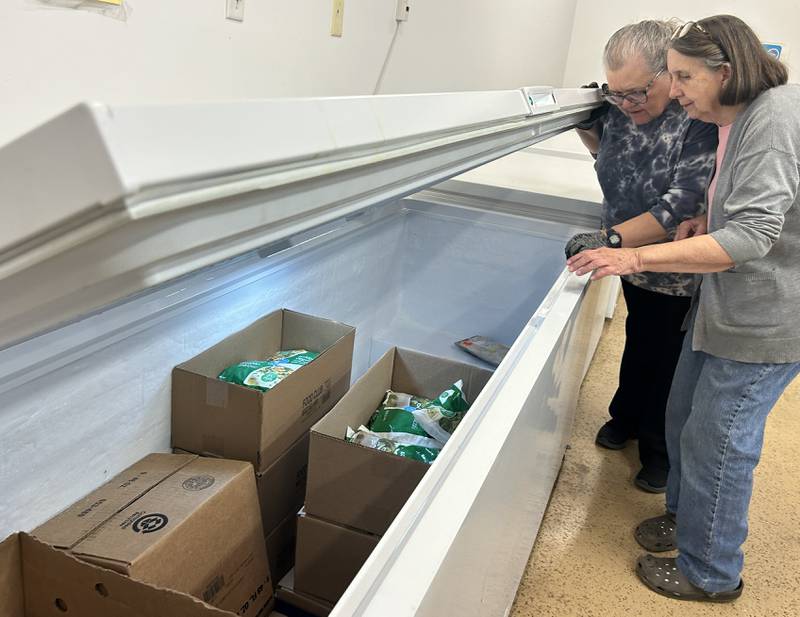 Volunteers Jean Dawson and Terry Pearson check out frozen items in one of the freezers at the Polo Lifeline Food Pantry  on Saturday, Nov. 15, 2025. The pantry, located at 113 Green Street, has seen an increase in clients due to the recent stoppage of SNAP benefits and federal government shutdown.