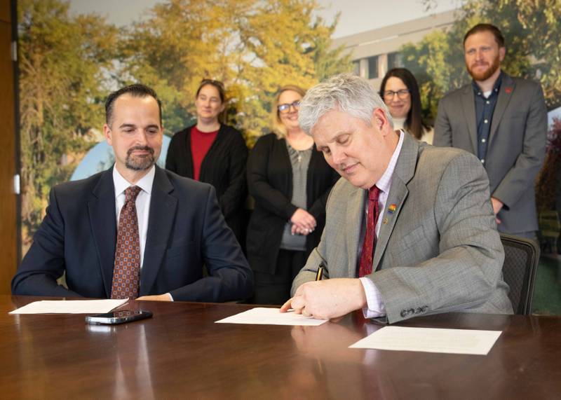 Jon Mandrell, Sauk Valley Community College vice president of academics and student services looks on as David Hellmich, college president, signs the agreement with SIU Carbondale on Wednesday, April 26, 2023.