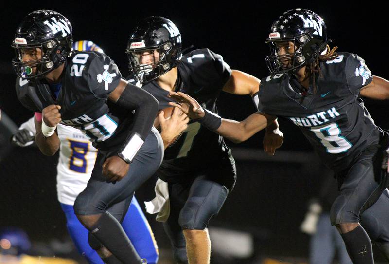 Woodstock North’s Parker Halihan, center, runs the ball as teammates David Randecker, left, and Max Dennison block against Johnsburg in varsity football on Friday Sept. 27, 2024, at Woodstock North High School in Woodstock.