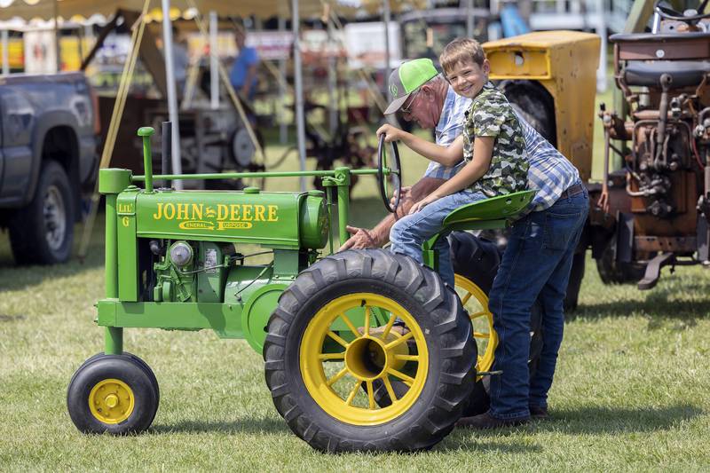 Doug Kreiser of Amboy fires up his homemade “Lil G John Deere” for Duke Bergfeld, 8, of Harmon Saturday, Aug. 3, 2024, at the Living History Antique Equipment Association’s farm show. Kreiser built two of these little tractors for kids to enjoy.