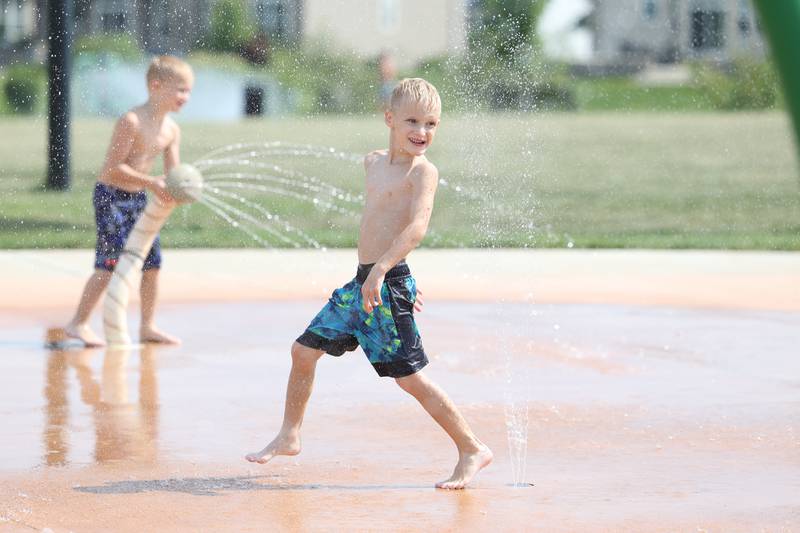 Tristan Winnan, center, 6-years-old, and his twin brother, Luke, play in the water at Wynstone Park in Shorewood on Wednesday, July 26.