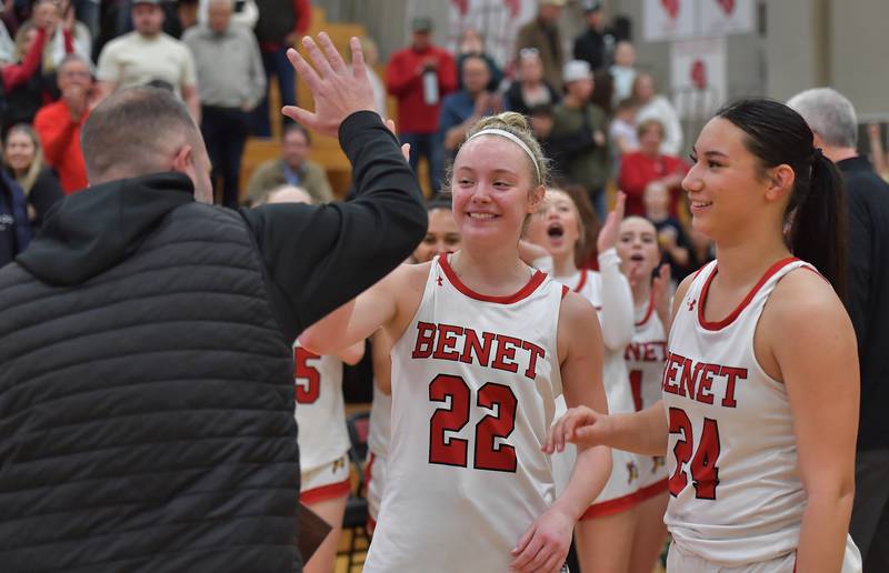 Benet’s Bridget Rifenburg (22) and Emma Briggs get a hight five from Benet Athletic Director Scott Lawler as he arrives to present them the championship plaque after the Class 4A Benet Regional final on February 19, 2026 at Benet Academy in Lisle.