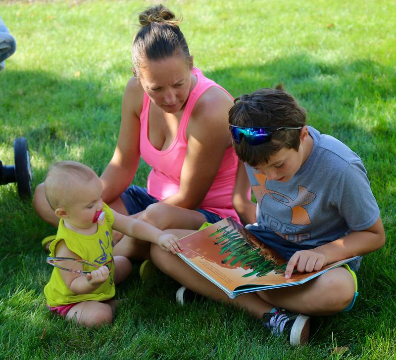 Jayden Devine reads a book to his sister Skylar Devine as mom, Sarah Padgett looks on at the Town and Country Public Library in Elburn on Saturday, Sept. 3, 2022.