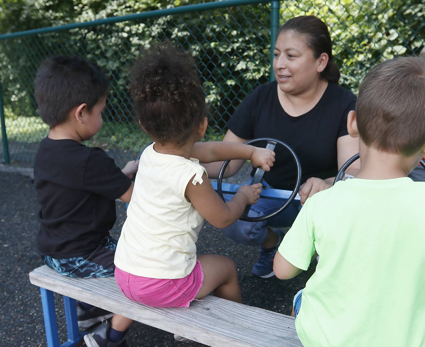 Teacher Nunez Arias interacts with a with children as they play on the playground Thursday, July 28, 2022, at the Friendship House, 100 South Main Street, in Crystal Lake. Childcare centers are struggling to find enough teachers to maintain operations.
