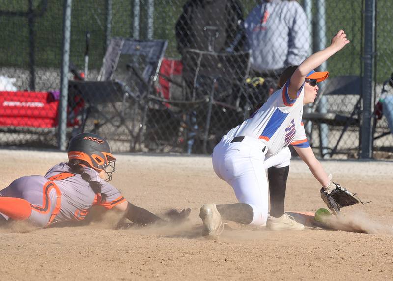 DeKalb's Isabel Aranda dives back to first as the throw gets past Genoa-Kingston's Lillian Provost Thursday, May 8, 2025, during their game at Genoa-Kingston High School.