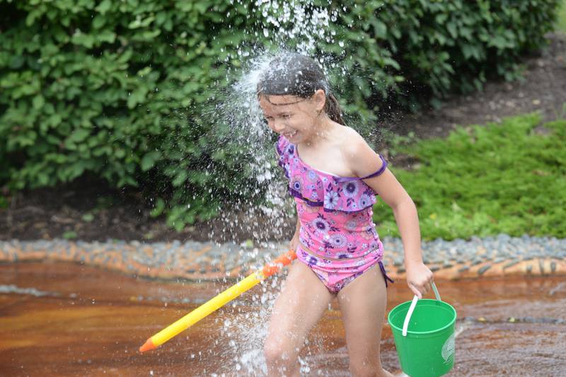 Emi Toppings, 6 of Oregon, runs through one of the water features at the Oregon Park District's Splash Pad at Oregon Park West on Tuesday, June 4, 2024. The park district hosted a pop-up and play event during the afternoon complete with a bubble machine and various types of water guns. The Splash Pad is located next to the shelter and playground at Park West and no admission is charged.