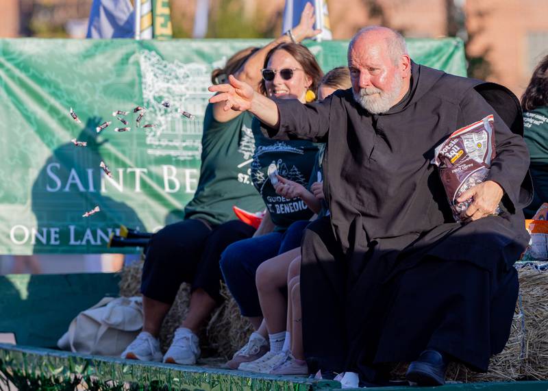 Fr Ronald Margherio tosses candy out to kids near city hall during the St. Bede homecoming parade on October 3, 2025 in Peru.