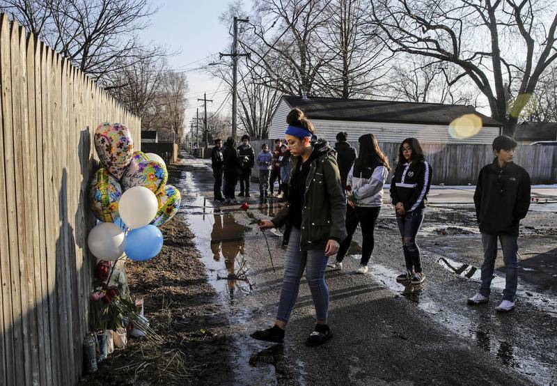 Friends of 13-year-old Javier Cayetano place balloons, candles and flowers on a memorial Friday in the alleyway on Morgan Street where Cayetano was shot Thursday night in Joliet.