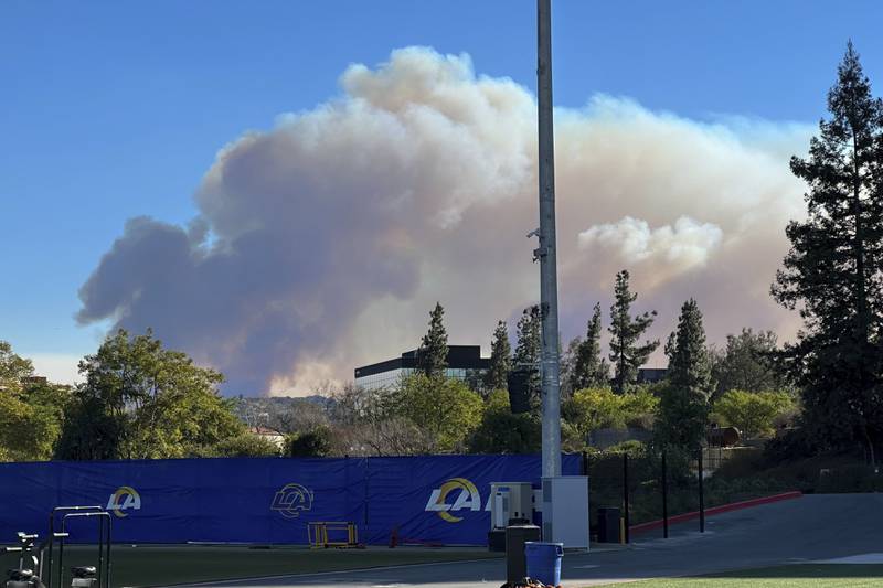 Smokes from a wildfire rises over the Los Angeles Rams NFL football practice facility in the Woodland Hills section of Los Angeles, Thursday, Jan. 9, 2025. (AP Photo/Greg Beacham)