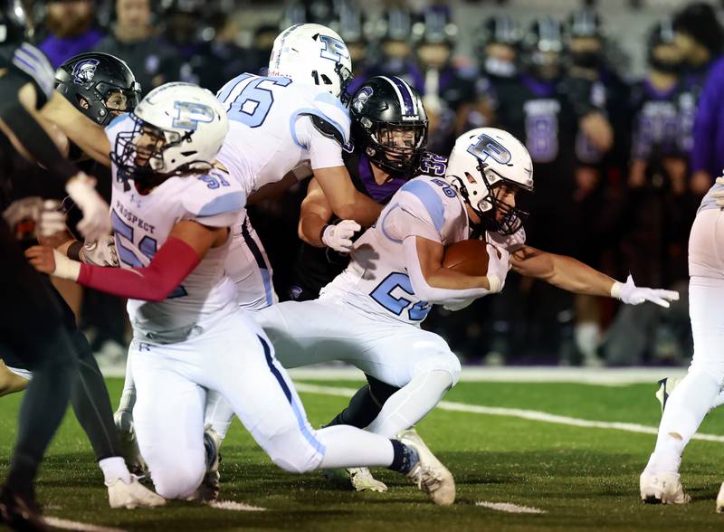Prospect's Matthew Donnelly (26)  reaches for extra yards as Downers Grove North's Baker Glomb (32) wraps him up during the IHSA Class 7A playoff football game Friday, Oct. 31, 2025 in Downers Grove.