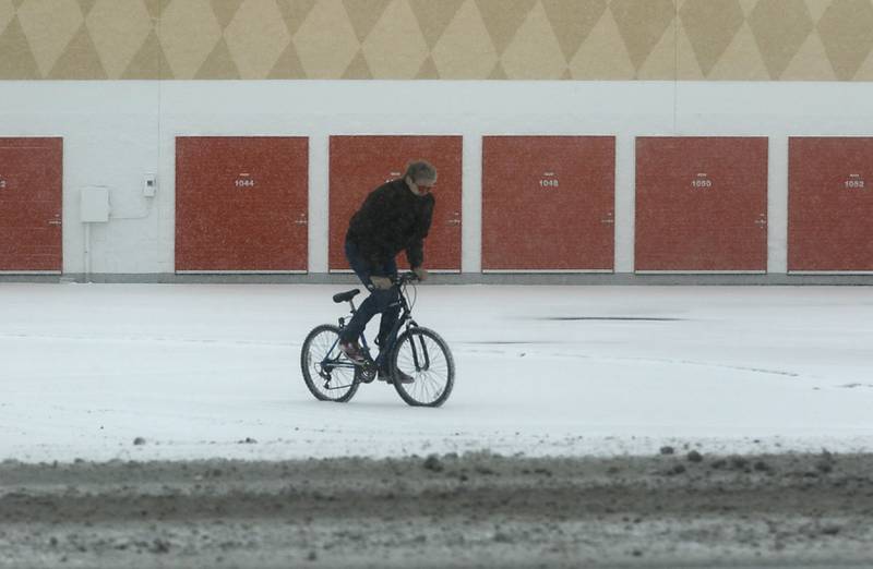 A man rides his bicycle through a snow covered parking lot on Wednesday, Feb. 12, 2025 in McHenry as a winter storm starts to bring heavy snow to the McHenry County area