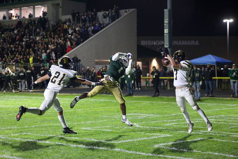 Herscher's Gaige Brown, right, nearly intercepts a pass intended for Bishop McNamara's Malachai Lee, center, in the end zone during Bishop McNamara's 38-14 victory in the IHSA Class 3A first round playoff game on Friday, Oct. 31, 2025.