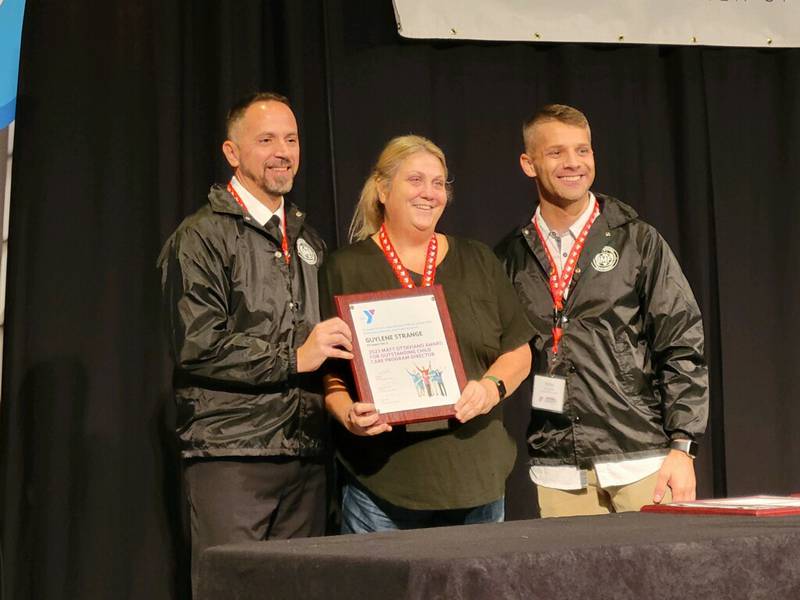 Guylene Strange (center), the youth and family director at the Ottawa YMCA, receives a plaque for being named the YMCA's Adam Ottaviano Outstanding Director of the Year Award.