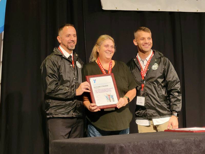 Guylene Strange (center), the youth and family director at the Ottawa YMCA, receives a plaque for being named the YMCA's Adam Ottaviano Outstanding Director of the Year Award.