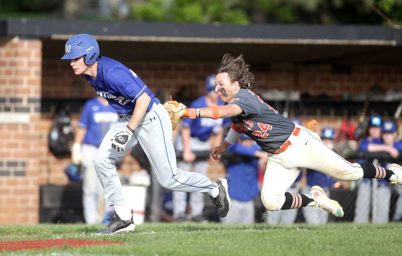 St. Charles East’s Jake Zitella (right) tags Wheaton North’s Charlie Strutzel out as he heads to home plate during a game in St. Charles on Monday, May 15, 2023.