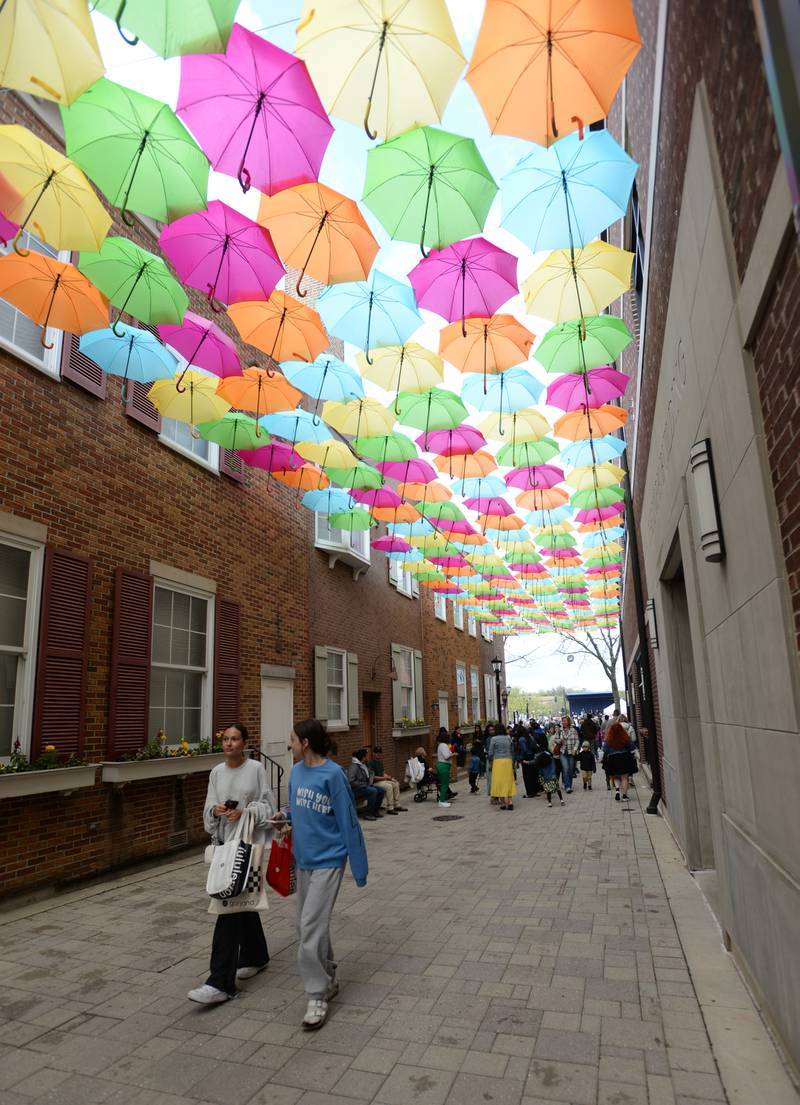 People walk through Schiller Court during the Public Art Commission's Umbrella Sky Project Opening Day Party held Saturday April 29, 2023.