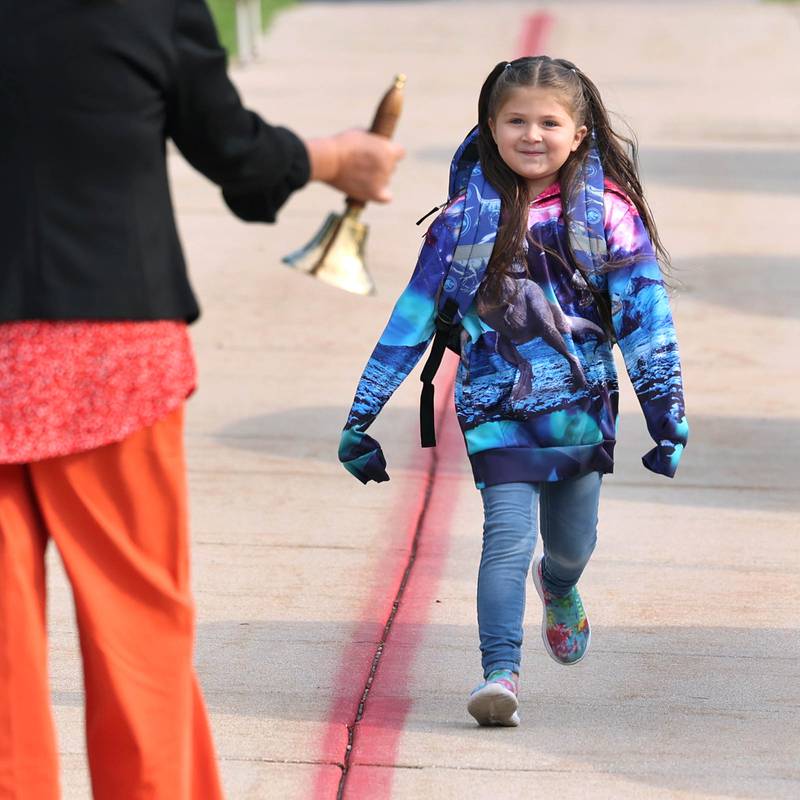 Gwendolyn Brooks Elementary School first grade student Zayli Contreras runs up to meet DeKalb School District 428 Superintendent Minerva Garcia-Sanchez so she can ring the bell Thursday, Aug. 17, 2023, as she arrives for the first day of the new school year.