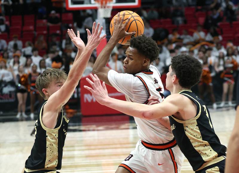 DeKalb's Bryan Miller goes between Sycamore's Xander Lewis (left) and Marcus Johnson Friday, Jan. 30, 2026, during the FNBO Challenge at the Convocation Center at Northern Illinois University in DeKalb.