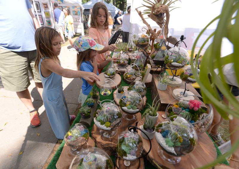 (Left to right) Felicity and Vivienne Nuseszynski and Emma Glennon of Glen Ellyn pick out some plant arranged art pieces to take home during the Glen Ellyn Art Festival on Sunday, Aug 24, 2024 at Lake Ellyn.