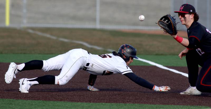 McHenry’s Jack Stecker, left, dives safely back to first base as Huntley’s AJ Putty fields a pick-off toss in varsity baseball at McHenry Friday night.
