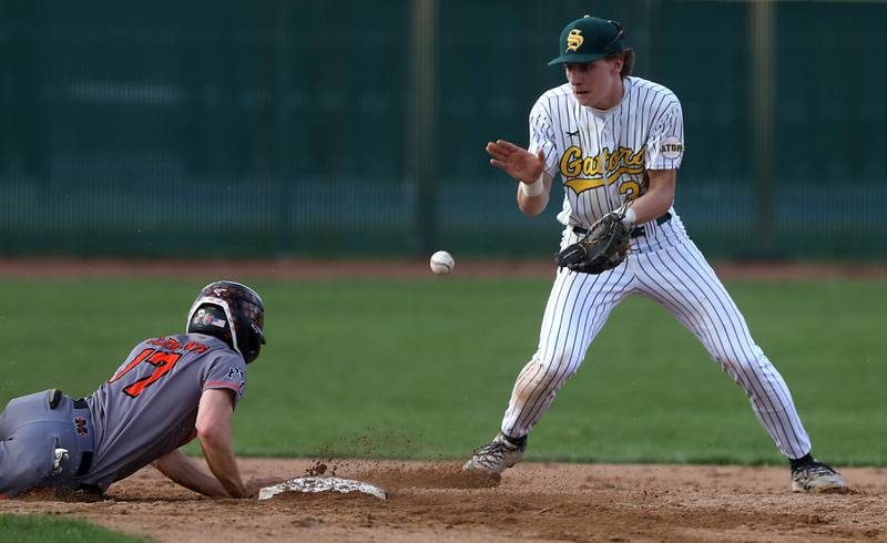 Crystal Lake South's Carson Trivellini fields a throw from the catcher as McHenry's Landon Clements dives back to second base during a Fox Valley Conference baseball game on Monday, April 13, 2026, at Crystal Lake South High School.