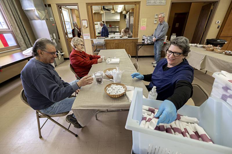 Susan Parker rolls ups up flatware while volunteering at the breakfast Wednesday, March 29, 2023. It takes 6-8 workers a day to efficiently cook and serve the 125 t0 150 meals a day. COVID moved the church from changing from a sit down breakfast to strictly carry-out.