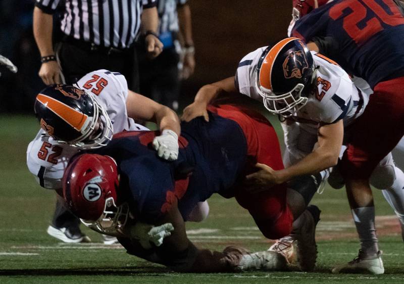 Oswego’s Matthew Egly (52) and Oswego’s Evan Brown (23) hit West Aurora's Trevon Tittle (32) for a loss in Aurora Oct. 4.