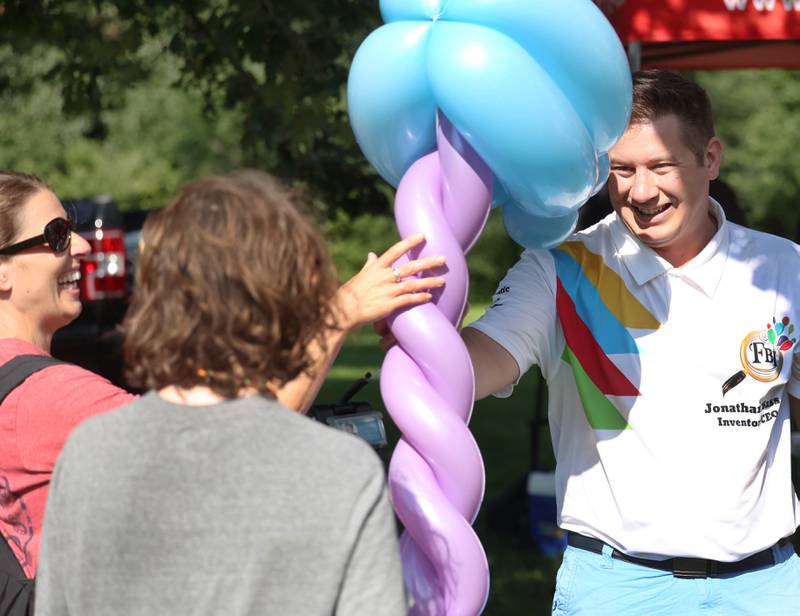 Jonathan Sass, from FBI Entertainment, hands an attendee a ballon creation he made for him during the Family Fun Fest Wednesday, July 17, 2024, at Hopkins Park in DeKalb.