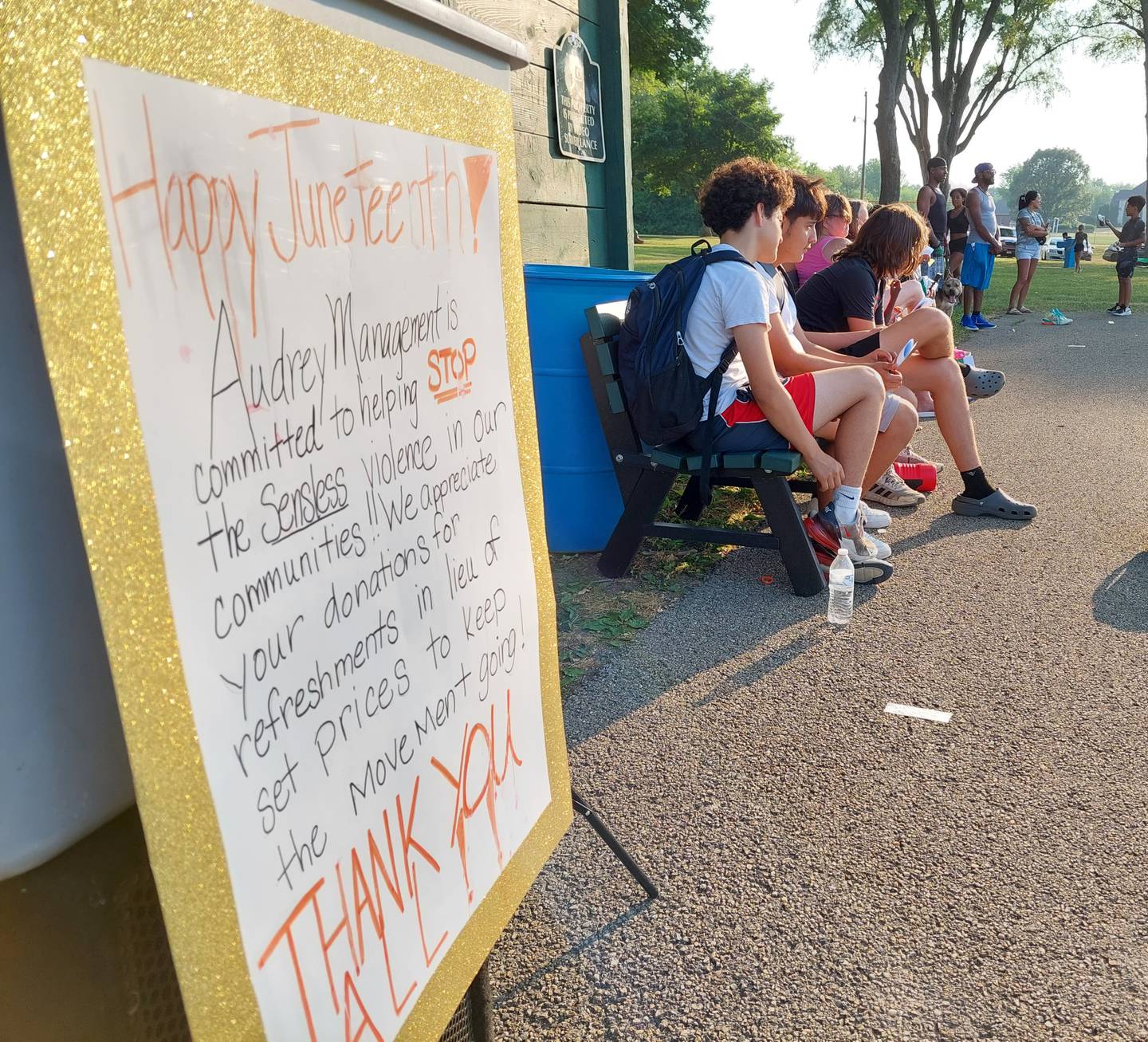 Youths sit along the basketball court and listen to speakers Monday, June 19, 2023, during a Juneteenth celebration at Kirby Park in Spring Valley.