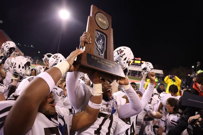 Mt. Carmel’s Tavon Rice hold up the championship trophy after the Caravan’s 35-10 win over Downers Grove North in the Class 7A championship on Saturday, Nov. 25, 2023 at Hancock Stadium in Normal.