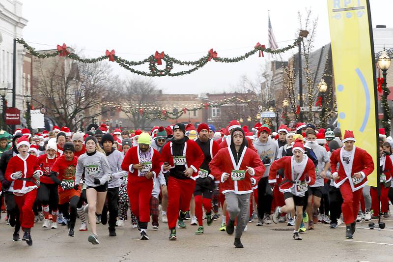 Some to the over 500 Santa Claus dressed runners, start their 5K race during the McHenry County Santa Run For Kids Sunday morning, Dec. 3, 2023, in Downtown Crystal Lake. The annual event raises money for agencies in our county who work with children in need.