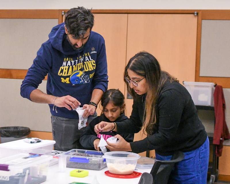 Saggar Patel, Leela Patel, 6, and Vanisa Patel put rice in hand sown bags for Memory Café to help those with memory loss warm up after heating up the rice bags to hold at the Elmhurst library on Monday Jan. 20, 2025, during the Martin Luther King Jr. Day of Service.