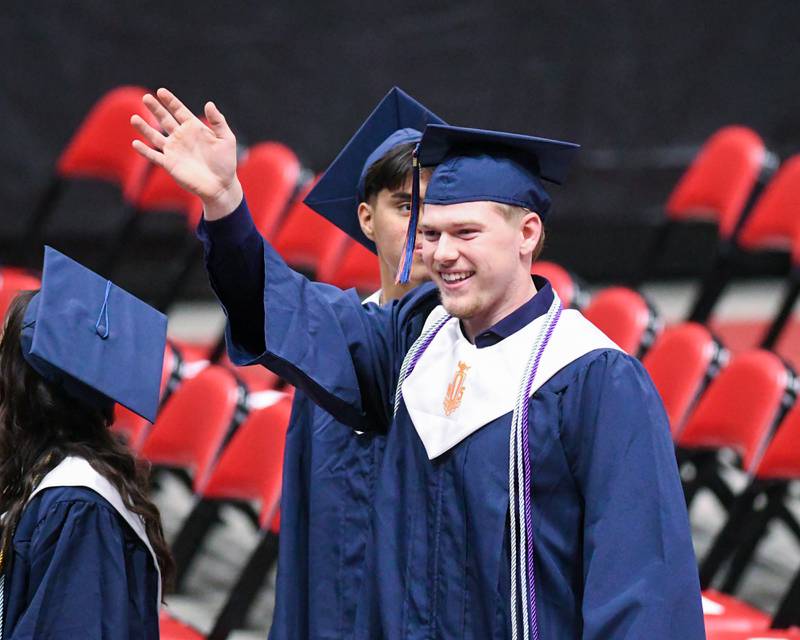 An Oswego High School graduate waves to audience members as he walks into the graduation ceremony on Saturday May 17, 2025, held at the Convocation Center in DeKalb.