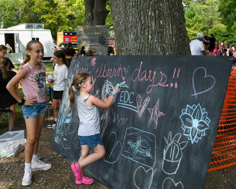 Sophia Petryka, 4, of Sycamore draws on a chalk board while her cousin Piper Bagnasco, 9, of Maple Park sees what she draws on Saturday Aug. 16, 2025, during Elburn Days held at Lions Park in Elburn.