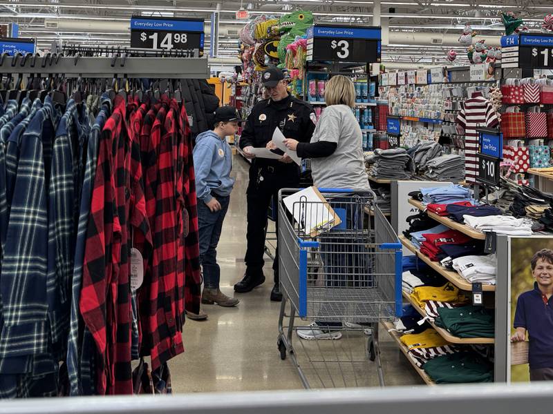 Coal City Police Chief Chris Harseim goes over the shopping list with Andy, Jaxten and a volunteer from Grundy County Heroes and Helpers.