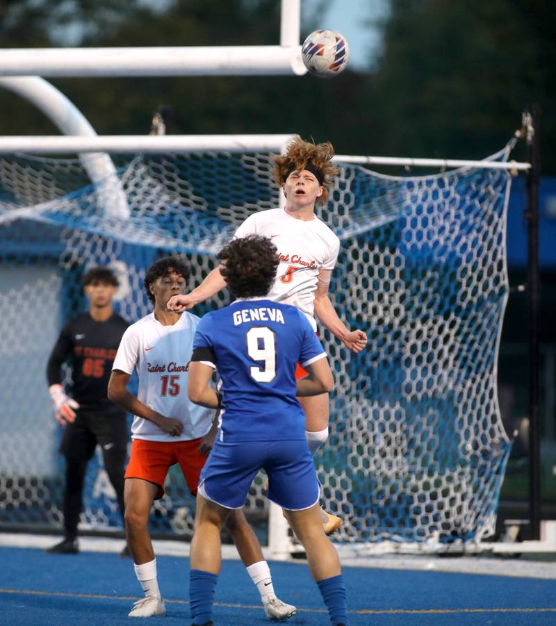 St. Charles East’s Jake Walker heads the ball surrounded by teammate Brandon Pinto and Geneva’s Trent Giansanti during a game at Geneva on Tuesday, Oct. 3, 2023.