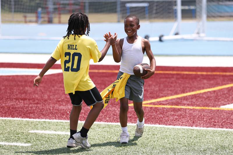 Miy'on Dismues, 8, of Kankakee, and Amari Jones, 8, of Bradley, celebrate after a touchdown during the Suga Summer Camp at Kankakee High School on Saturday, July 5, 2025.