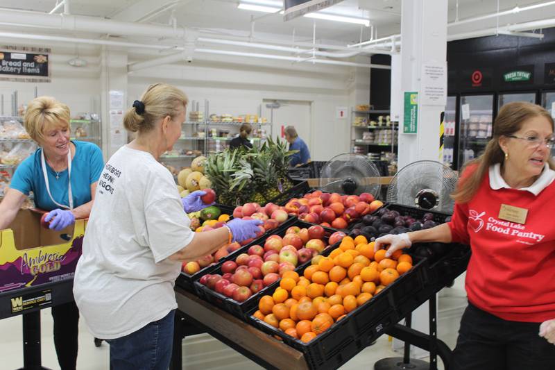 Crystal Lake Food Pantry volunteers stock the produce shelves before another busy day.