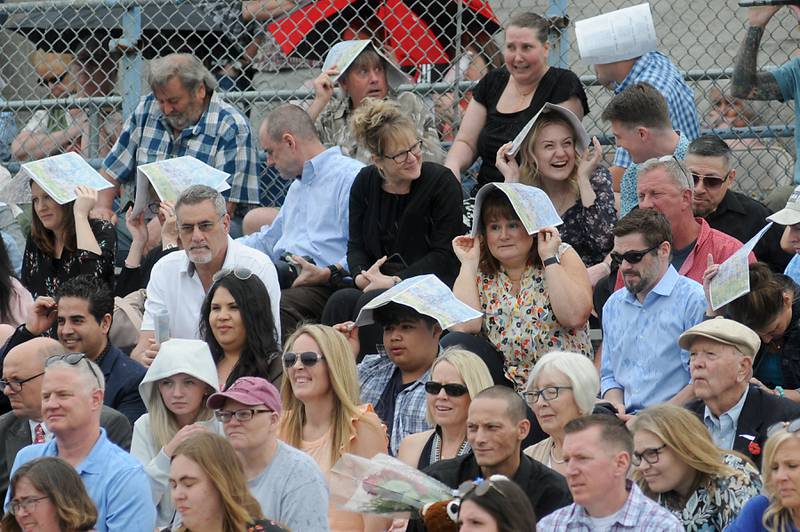 People use their programs to cover their heads as the rain begins to fall Sunday, May 15, 2022, during the Woodstock High School graduation ceremony in Woodstock.