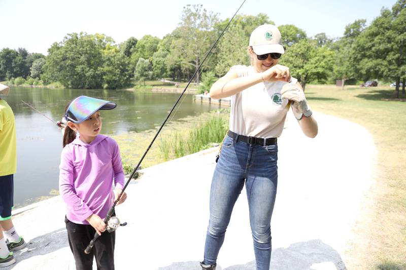 Caitlin Chex, a seasonal ranger with the DuPage County Forest Preserve District helps 10-year-old Noelle Cho of Wheaton with the fish she caught during the Wheaton Police Department and DuPage County Forest Preserve Police Cops & Bobbers community fishing event at Herrick Lake Forest Preserve in Wheaton on Wednesday, June 7, 2023.