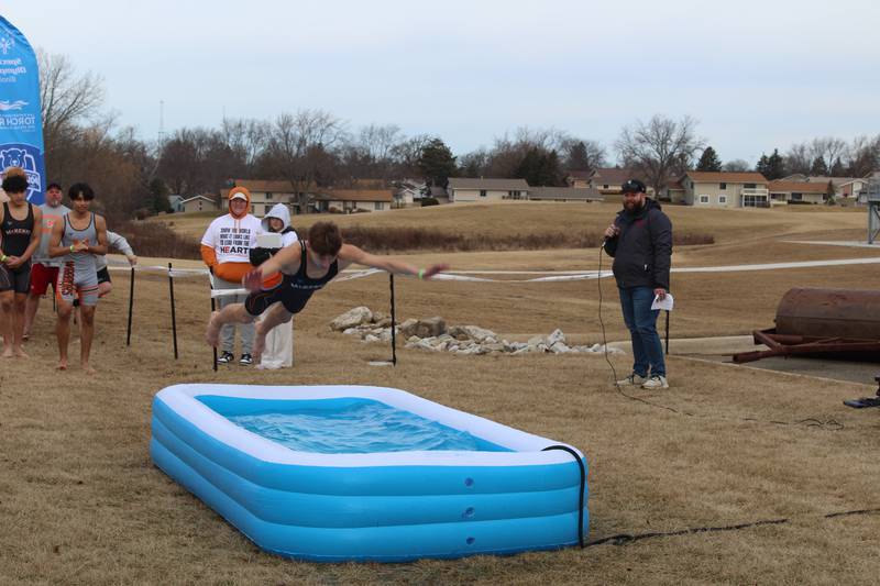 A wrestler on the McHenry Community High School boys wrestling team belly flops into an inflatable pool during the school's first polar plunge on Feb. 1, 2025.