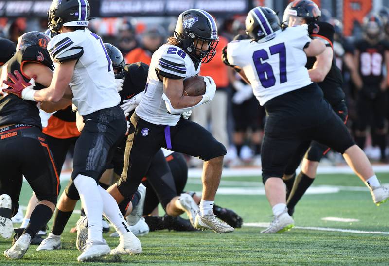 Downers Grove North's Noah Battle (20) breaks through a hole in the Lincoln-Way West defense with the help of blocks by teammates Colton Ford (67) and Cael Brezina (left) during an IHSA Class 7A quarterfinal game on Nov. 11, 2023 at Lincoln-Way West High School in New Lenox.